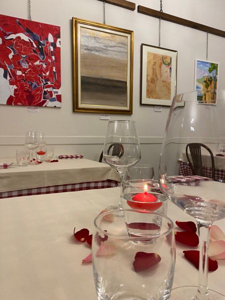 Tavolo apparecchiato con candele accese e quadri alle pareti