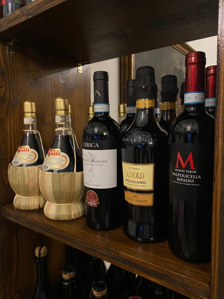 Scaffale con bottiglie di vino e ampolle di aceto balsamico