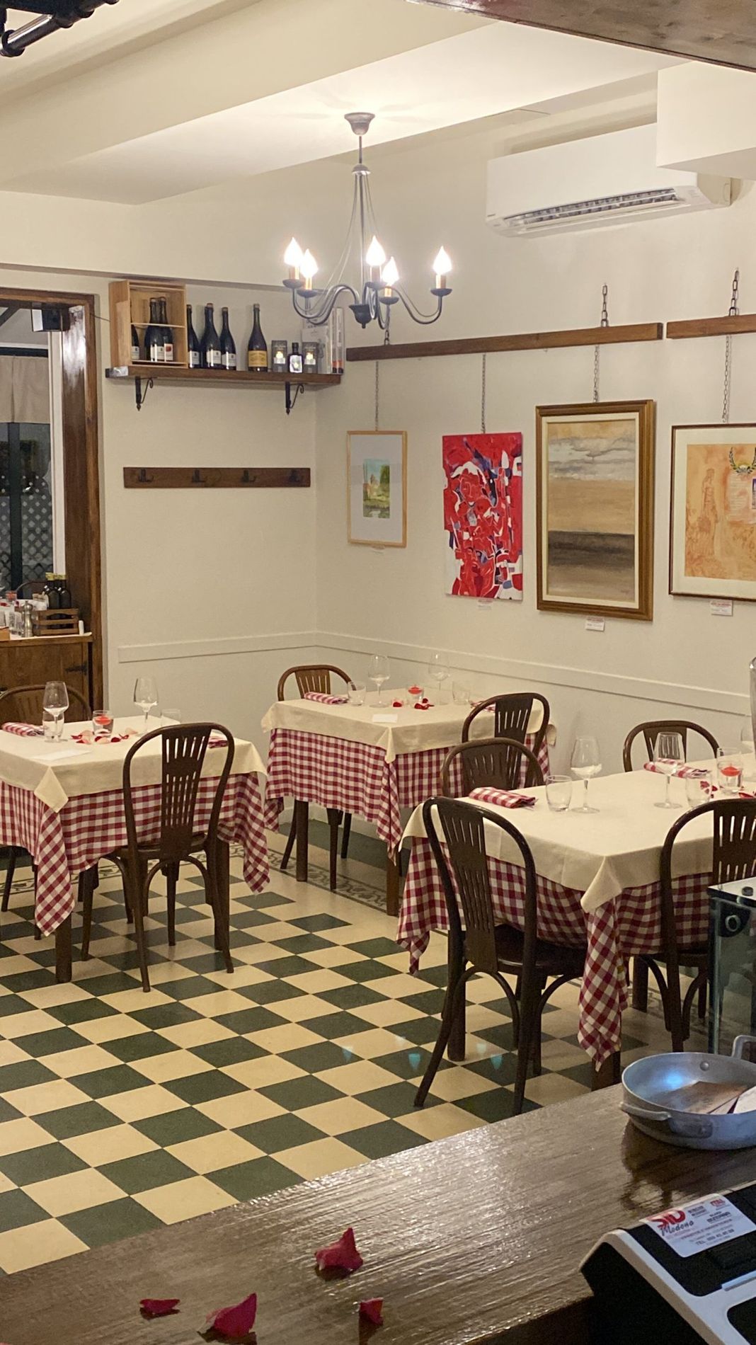La sala della Locanda Redecocca: tovaglie a quadri rossi, pavimento a scacchi e lampadario acceso