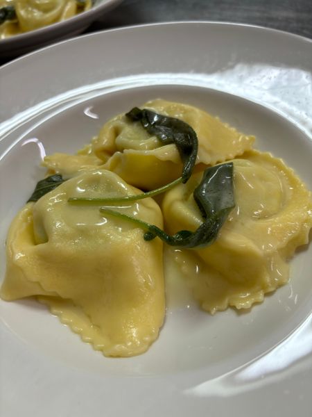 Piatto di tortelloni di zucca conditi con burro e foglie di salvia